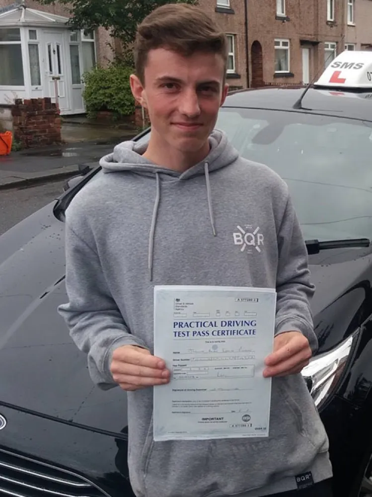 An SMS Driving School pupil holding their practical driving test pass certificate after passing at Rhyl test centre