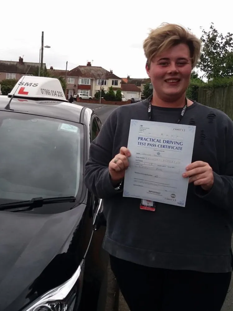 An SMS Driving School pupil holding their driving test pass certificate at Rhyl test centre