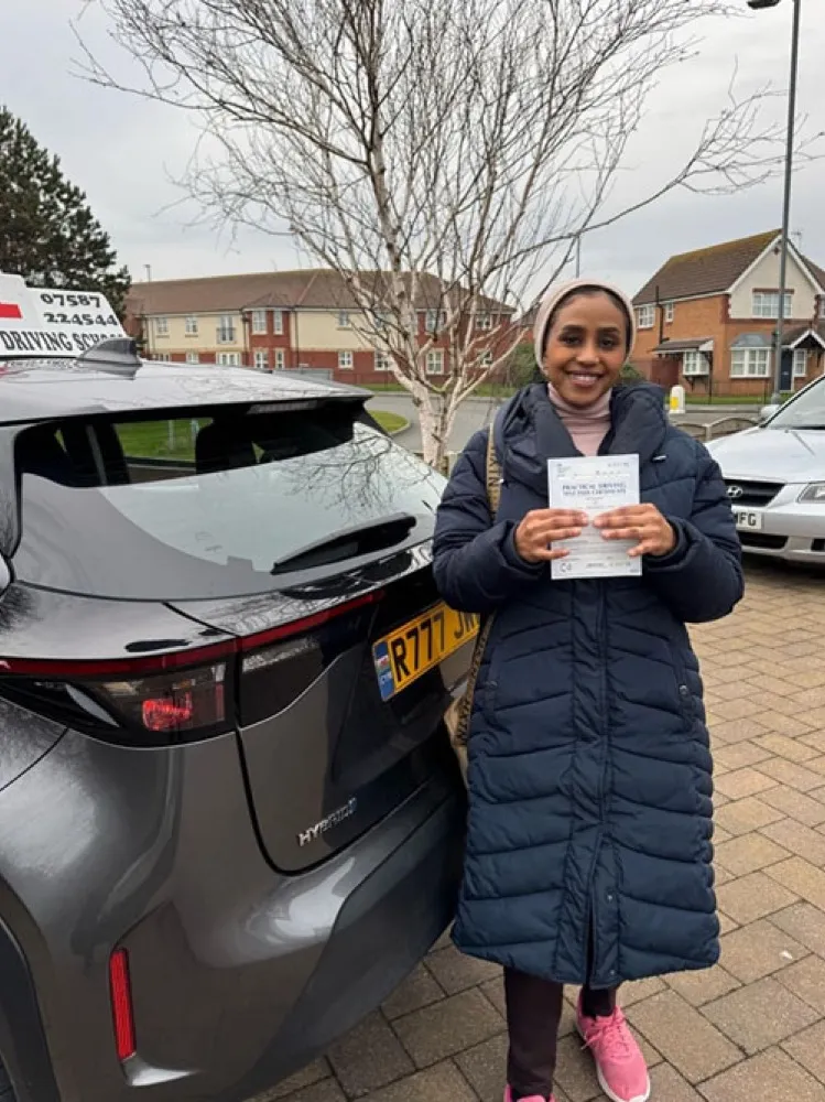 An SMS Driving School pupil holding their practical driving test pass certificate after passing at Rhyl test centre