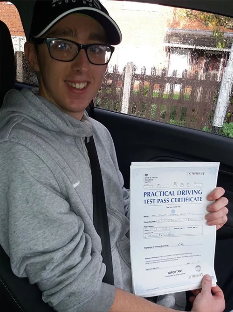 An SMS Driving School pupil holding their practical driving test pass certificate after passing at Rhyl test centre