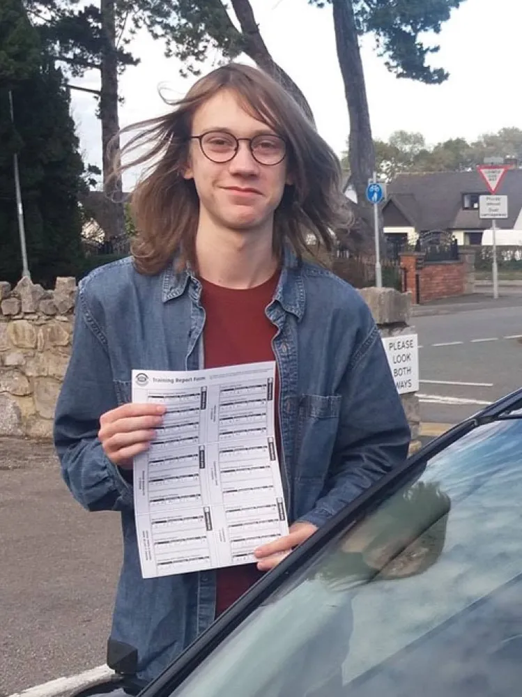 An SMS Driving School pupil holding their practical driving test pass certificate after passing at Rhyl test centre