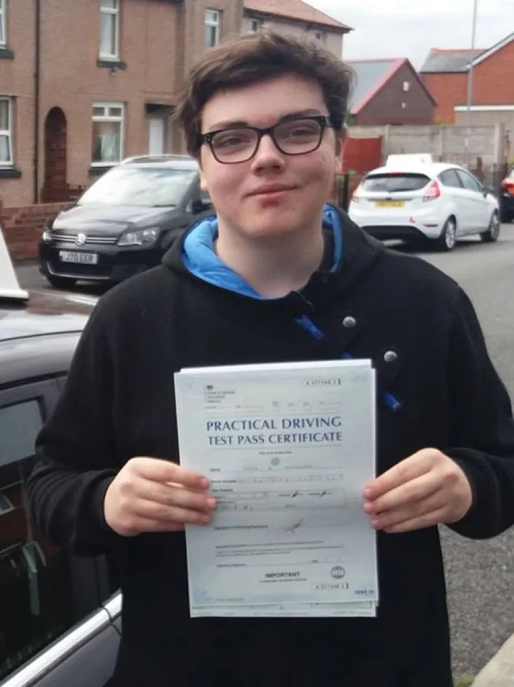 An SMS Driving School pupil holding their practical driving test pass certificate after passing at Rhyl test centre