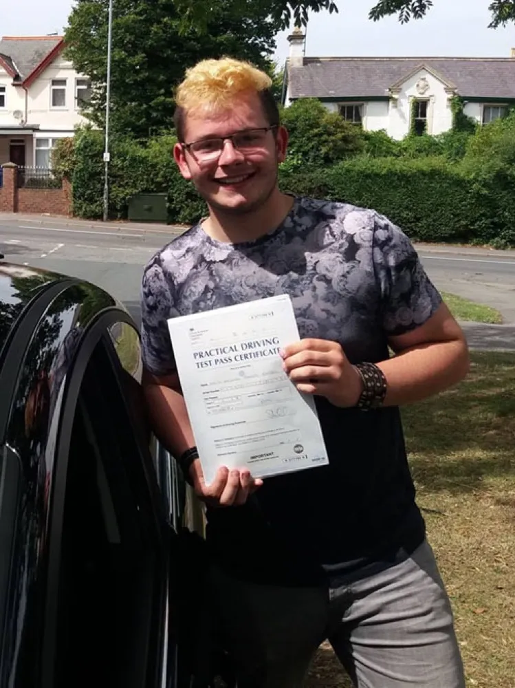 An SMS Driving School pupil holding their driving test pass certificate at Rhyl test centre